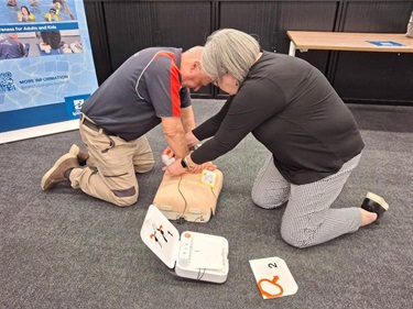 Two adults practicing CPR on mannequin 