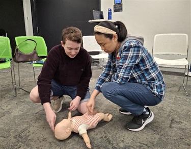 Two adults practicing CPR on mannequin 