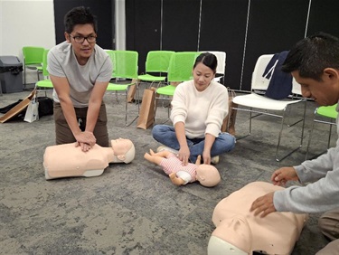 Three adults practicing CPR on mannequin 