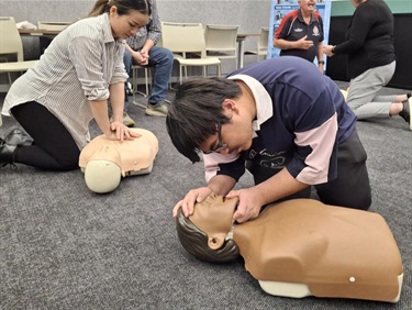 Two adults practicing CPR on mannequin 